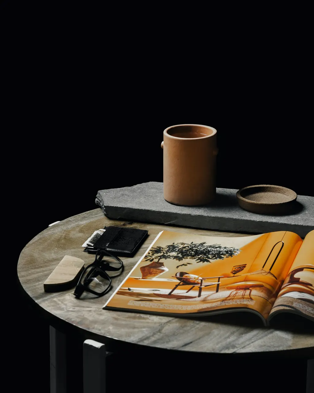 An open magazine, glasses and stoneware on a marble side table